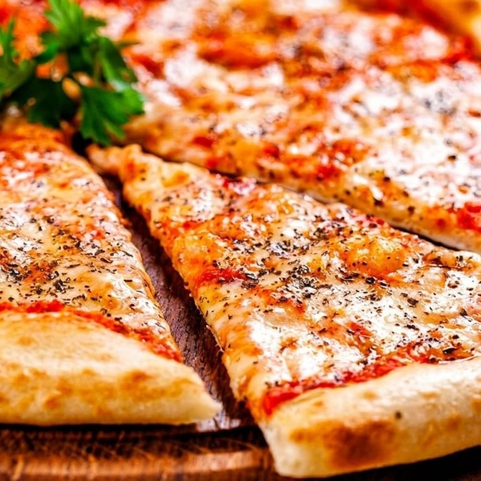 A whole cheese pizza with one slice removed, garnished with fresh parsley on a wooden board.